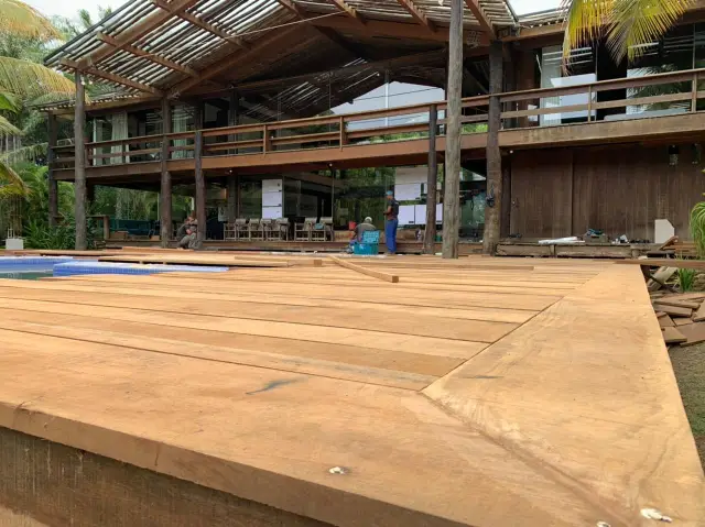 Réguas largas de madeira sendo assentadas no deck do Condomínio Txai, com a casa ao fundo