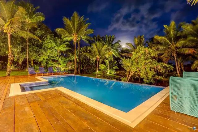Deck e piscina iluminados à noite no Condomínio Txai