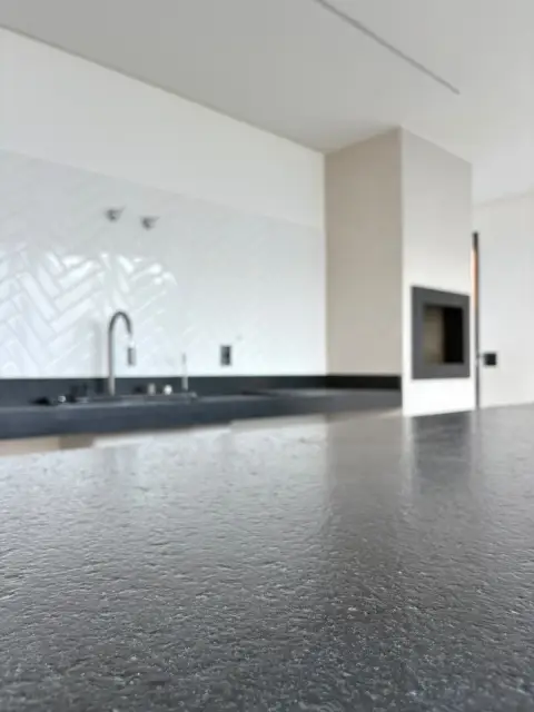 Cozinha ampla com bancada escura e luz natural