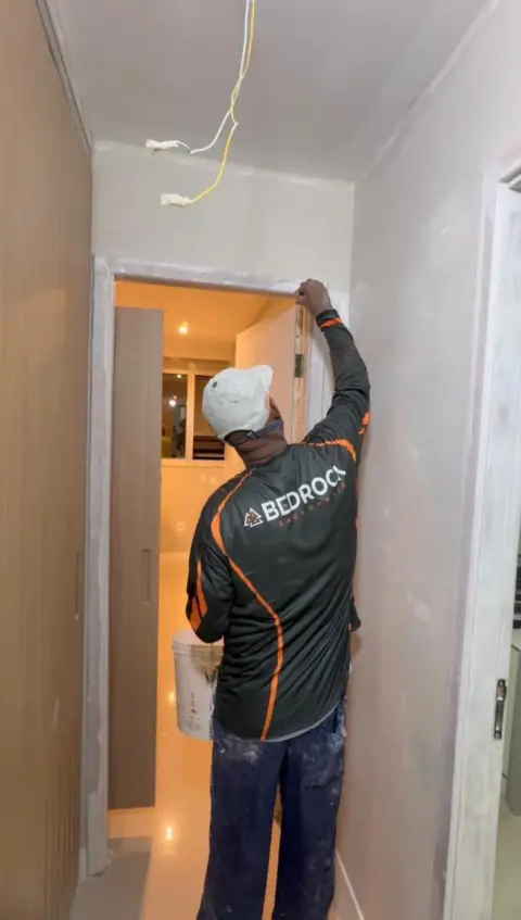 Profissional da Bedrock instalando acabamento em uma porta